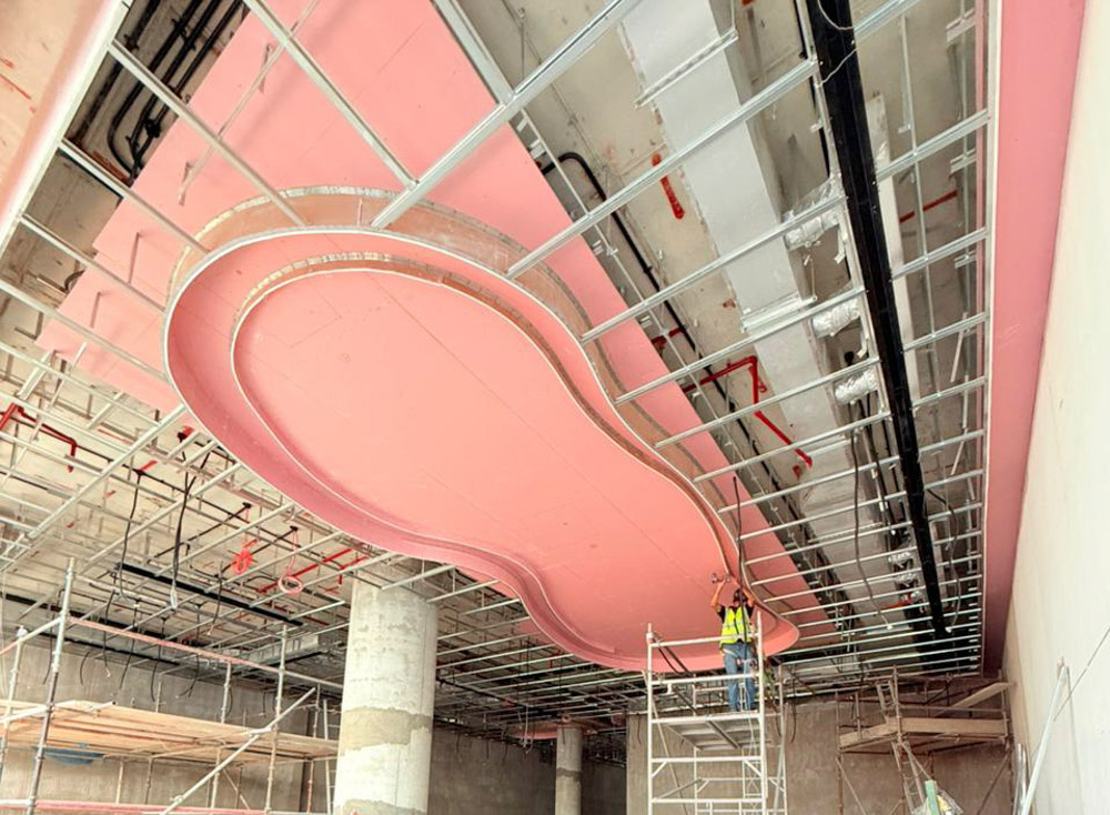 Beach Walk Iii By Imtiaz Construction scene showcasing a pink ceiling design with scaffolding and a worker installing it.